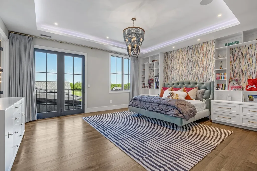 Elegant primary bedroom with custom wallpaper, tufted headboard, built-in shelving, and French doors opening to a balcony in a Mount Juliet luxury home.