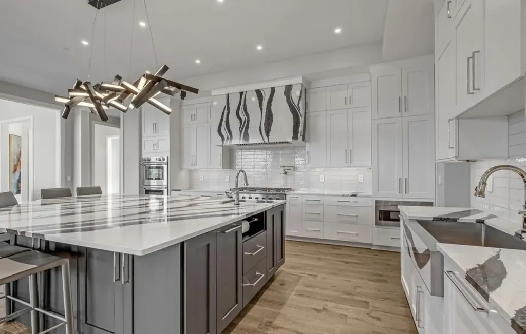 Contemporary kitchen with waterfall marble island, sculptural pendant lighting, and custom cabinetry in a modern Mount Juliet luxury home.