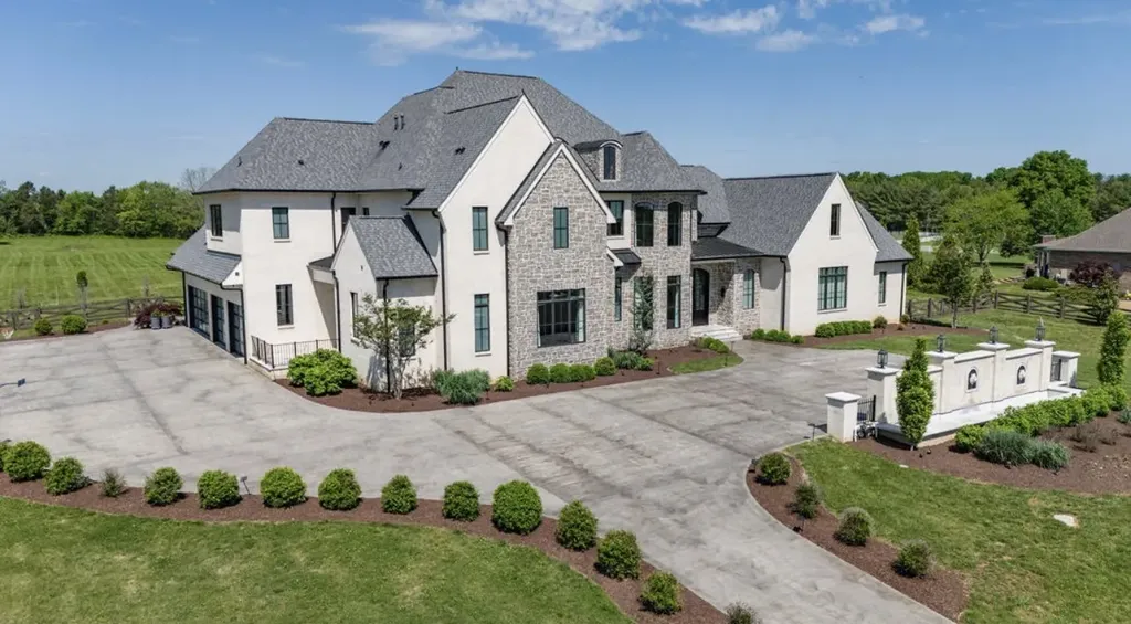 Side front view of modern French-inspired luxury estate with stone accents, manicured driveway, and landscaped grounds in Mount Juliet, Tennessee.