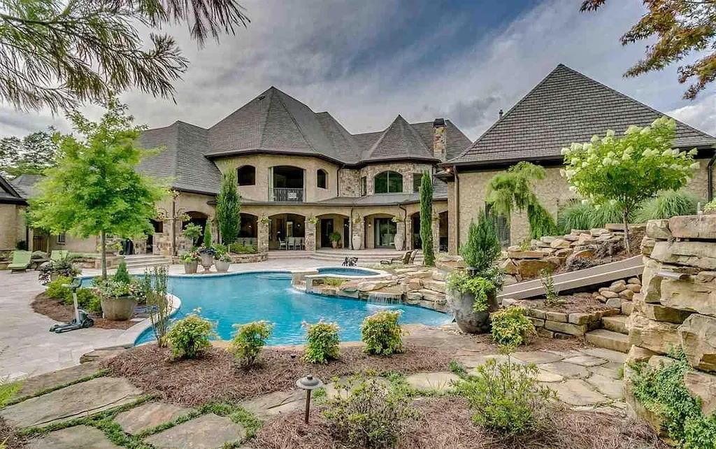 Luxury backyard pool at 2470 Cahaba Valley Rd, Indian Springs, Alabama, featuring cascading waterfalls, lush landscaping, and a resort-style terrace, highlighted in Luxury Houses Magazine.