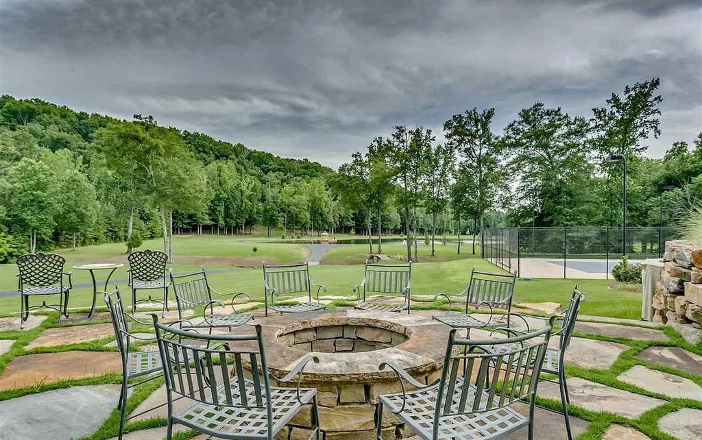 Luxury outdoor fire pit and tennis court at 2470 Cahaba Valley Rd, Indian Springs, Alabama, surrounded by lush greenery and mountain views, featured in Luxury Houses Magazine.