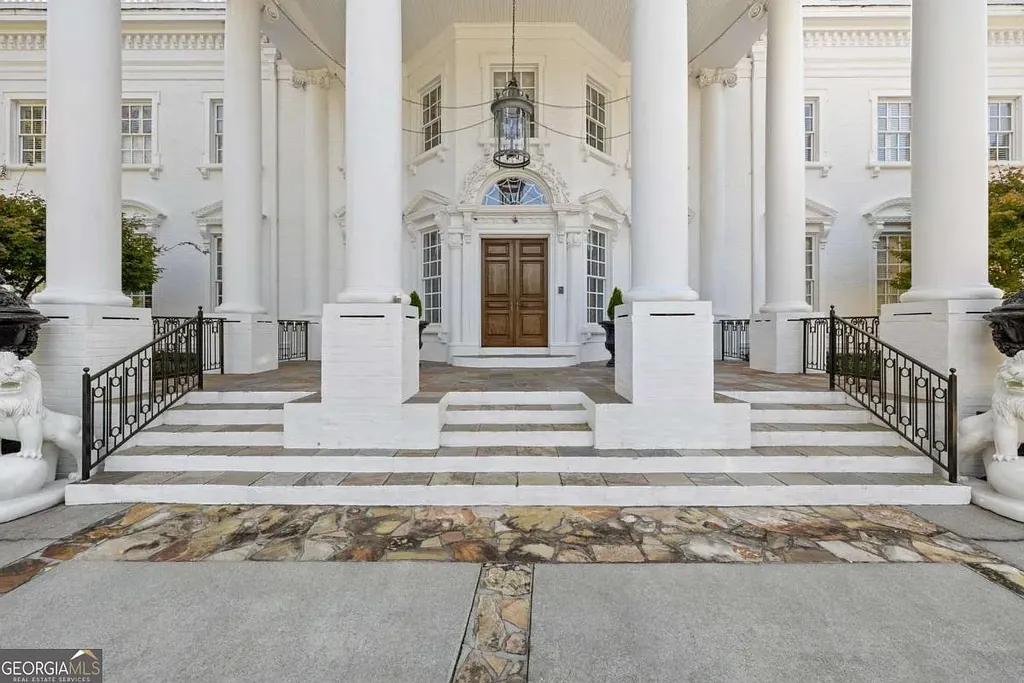 Close-up of the main entrance to the Atlanta White House, highlighting the massive white columns, brown wooden front door, and lion statues on the steps.