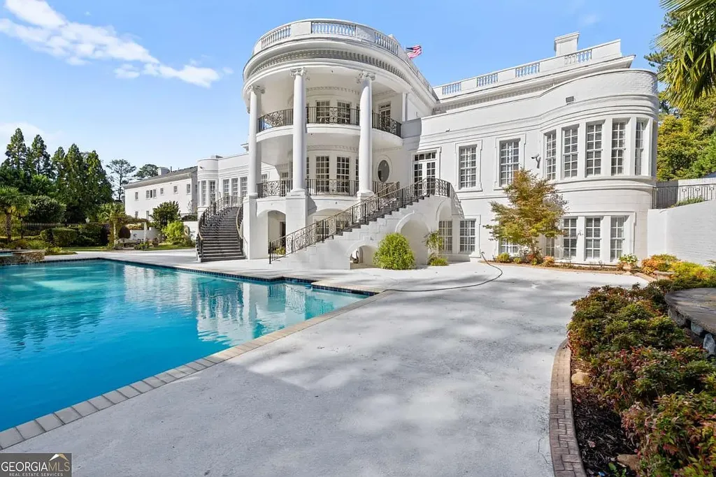 The extensive sun-drenched pool deck and oversized swimming pool on the rear elevation of the Atlanta White House, beneath the curved neoclassical balconies.