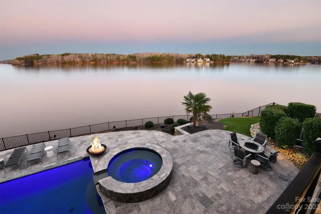 A Breathtaking Modern Masterpiece Overlooking Lake Tillery, North Carolina 11 Infinity pool and spa at 4059 Old Timber Way, Norwood, North Carolina, overlooking Lake Tillery at sunset, featuring fire pit, lounge chairs, and waterfront terrace.