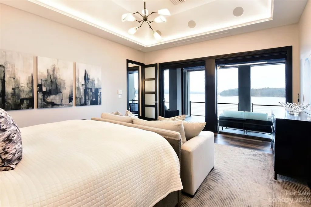 A Breathtaking Modern Masterpiece Overlooking Lake Tillery, North Carolina 5 Primary bedroom at 4059 Old Timber Way, Norwood, North Carolina, featuring lakefront balcony, modern art decor, and elegant contemporary furnishings.