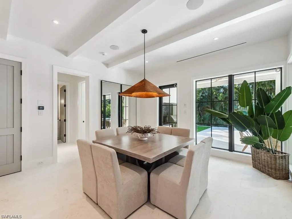 Front exterior view of 424 Spinnaker DR in Naples, showing gated courtyard, lime-washed brick, and lush landscaping.