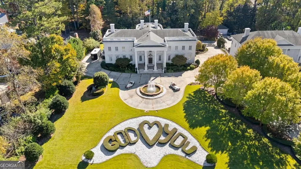 Aerial view of the $35M Atlanta White House estate, showing the neoclassical mansion, circular drive, and a large heart-shaped hedge with the phrase "GOD [HEART] YOU" on the lawn.