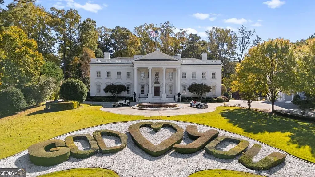 The front lawn of the Atlanta White House showing the decorative gravel and hedge spelling "GOD [HEART] YOU," with the mansion and central fountain in the background.