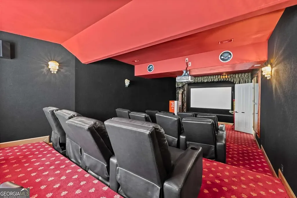 The private home theater inside the Atlanta White House's terrace level, featuring tiered seating with black leather recliners and red carpet.