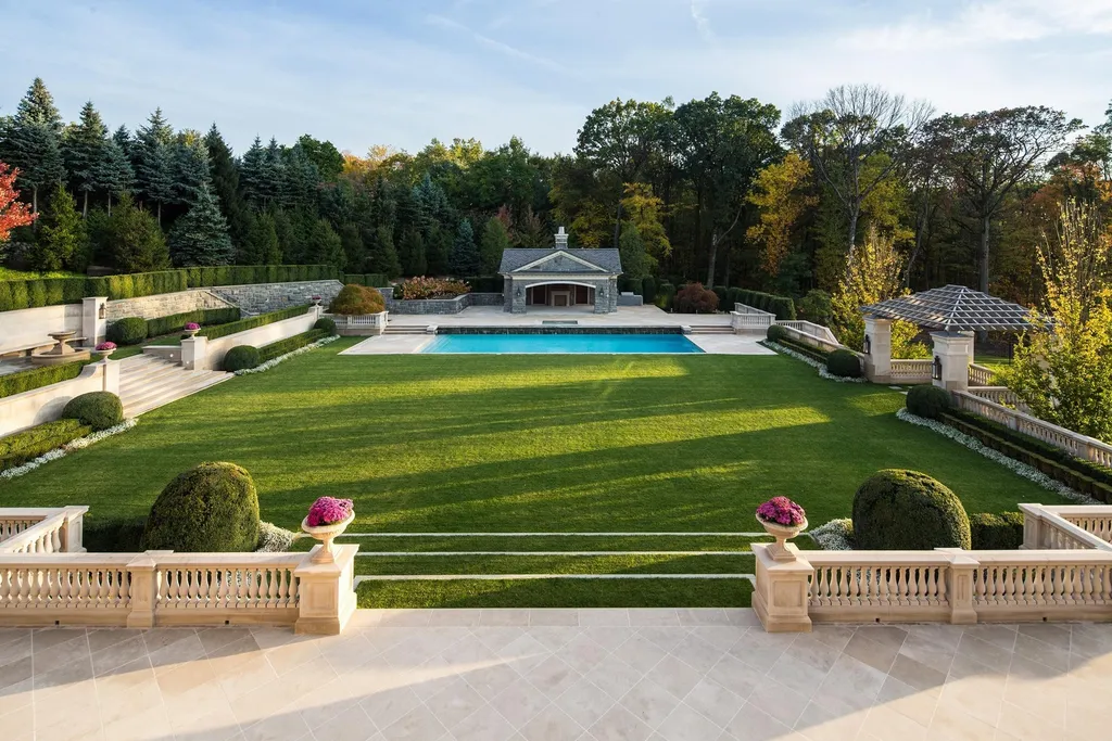 Step Inside One of America’s Most Extraordinary Modern Estates in Alpine 11 Expansive manicured backyard at 1 Frick Drive Alpine New Jersey featuring a large rectangular pool pool house stone terraces and formal landscaped gardens.