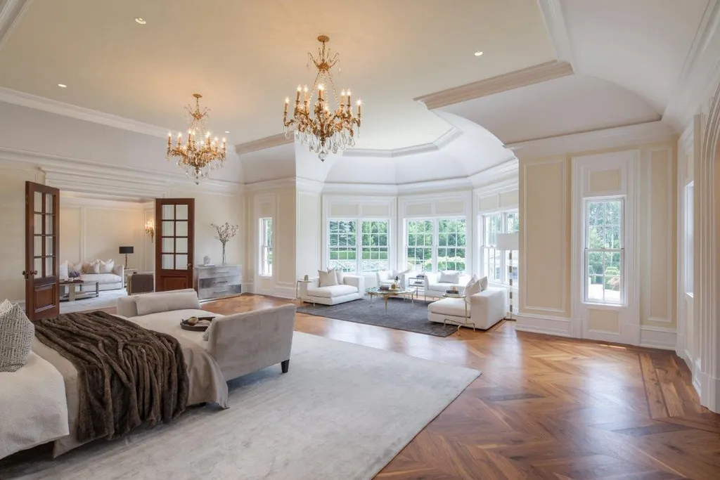 Step Inside One of America’s Most Extraordinary Modern Estates in Alpine 8 Expansive luxury primary suite at 1 Frick Drive Alpine New Jersey featuring ornate chandeliers sitting areas large windows and elegant wood flooring.