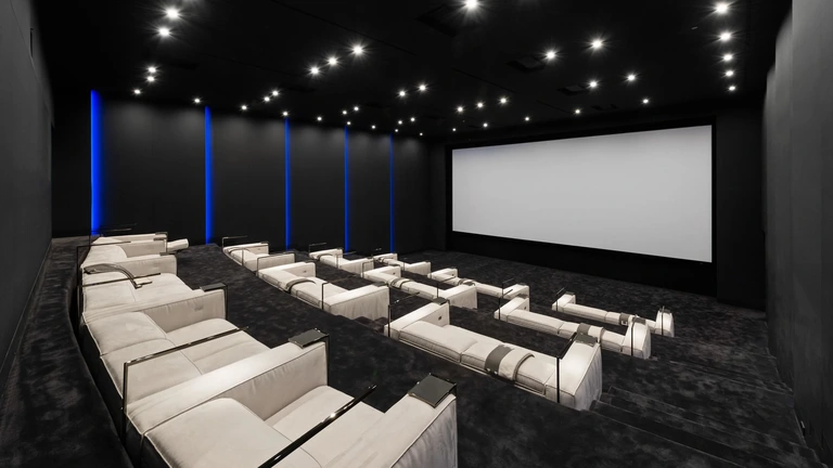 Interior view of the 50-seat private cinema inside The One, featuring plush white seating, dark walls, and a massive screen for luxury viewing.