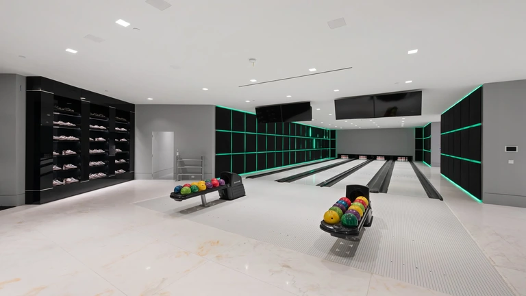 Interior shot of the four-lane bowling alley inside The One, the biggest home in Los Angeles, featuring marble floors and modern neon lighting