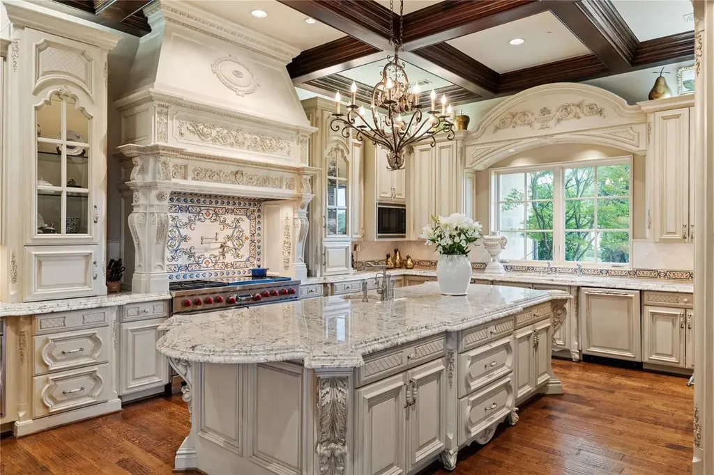 Château Lumièr in McKinney Lists for $14.65 Million as a French Chateau Estate Spanning Fifteen Wooded Acres 7 Chef’s kitchen inside Château Lumièr at 1201 Gray Branch Rd in McKinney featuring custom cabinetry an oversized marble island ornate range hood detailed millwork and wood beam ceilings.