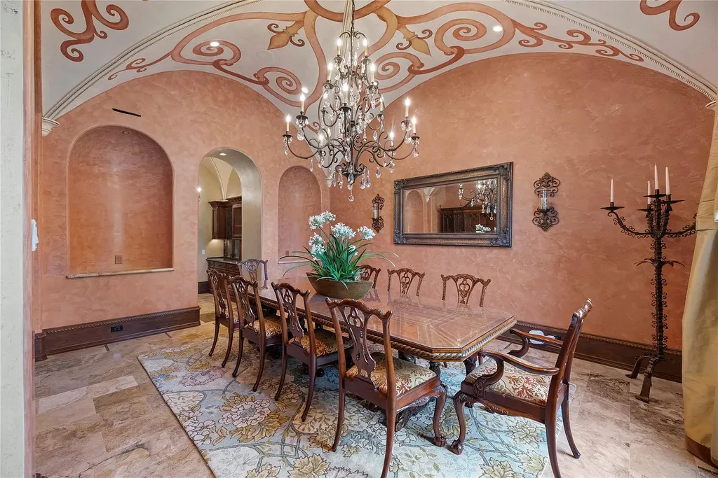 A Mediterranean Masterpiece Rising Above the Woodlands of Magnolia, Texas Seeks for $11,500,000 6 Formal dining room in the Mediterranean estate at 38262 Windy Ridge Trail, Magnolia, Texas, featuring a long carved wood dining table, upholstered chairs, hand-painted arched ceiling, textured terracotta walls, and an ornate chandelier.