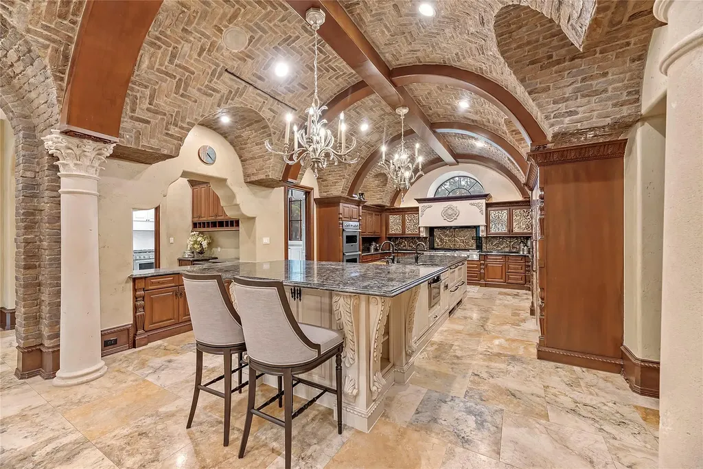 A Mediterranean Masterpiece Rising Above the Woodlands of Magnolia, Texas Seeks for $11,500,000 8 Expansive gourmet kitchen at 38262 Windy Ridge Trail in Magnolia, Texas, featuring barrel-vaulted brick ceilings, ornate columns, a large granite island, custom wood cabinetry, and luxury appliances.