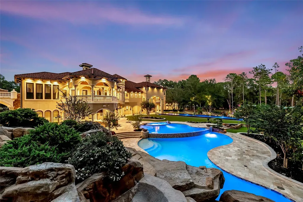 A Mediterranean Masterpiece Rising Above the Woodlands of Magnolia, Texas Seeks for $11,500,000 13 Expansive resort-style pool complex at 38262 Windy Ridge Trail in Magnolia, Texas, featuring multi-tiered pools, natural rock landscaping, lush gardens, and the illuminated Mediterranean-style mansion at sunset.