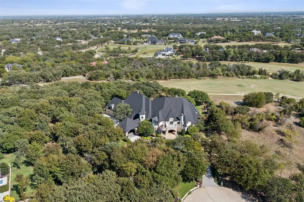 A $6.975 Million Steel Framed Estate Anchors Tour 18’s Most Enduring Address 11 Aerial view of 5700 Masters Ct in Flower Mound, Texas, surrounded by mature trees and golf course landscape