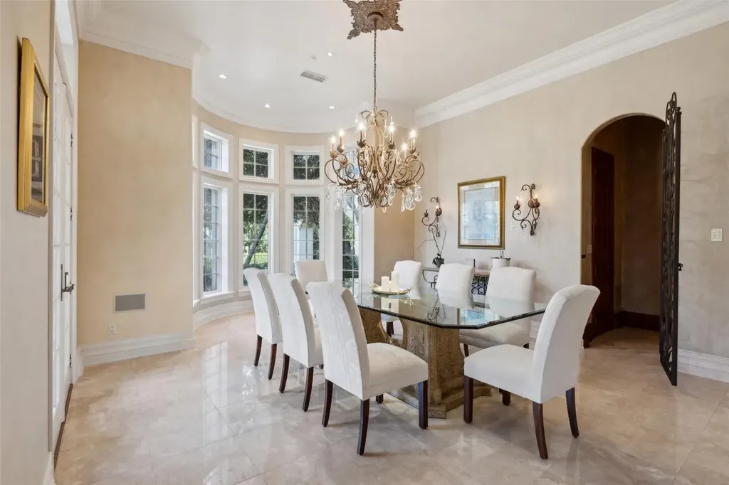 A $6.975 Million Steel Framed Estate Anchors Tour 18’s Most Enduring Address 5 Formal dining room with chandelier and curved window wall at 5700 Masters Ct in Flower Mound, Texas