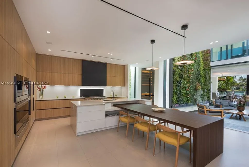 Waterfront exterior view of a tropical modern luxury residence at 6480 Allison Rd in Miami Beach, featuring floor-to-ceiling glass, resort-style pool, and bayfront access.