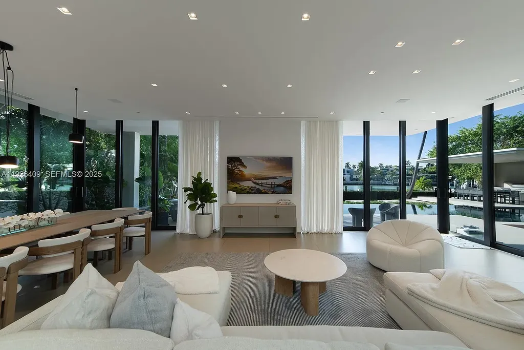 Waterfront exterior view of a tropical modern luxury residence at 6480 Allison Rd in Miami Beach, featuring floor-to-ceiling glass, resort-style pool, and bayfront access.