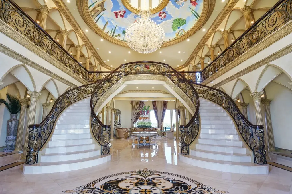 A Venetian Inspired Plano Estate Lists for 7.5 Million as a Rare Architectural Masterpiece in Kings Gate 3 Grand double staircase inside the Venetian inspired estate at 6509 Sudbury Rd in Plano featuring ornate ironwork marble steps a chandelier and a hand painted dome ceiling.