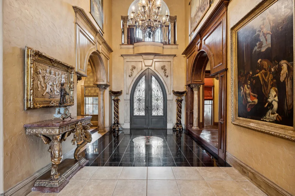 Castle Estate Heads to Auction at 6 Million as a Hilltop Masterpiece in Fort Worth 3 Grand foyer inside the castle estate at 9553 Bella Terra Dr Fort Worth Texas featuring arched doorways ornate wood paneling classical artwork and a chandelier beneath a soaring ceiling