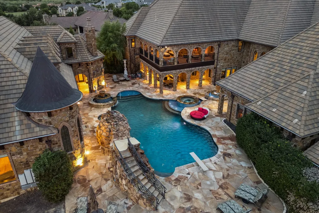 Castle Estate Heads to Auction at 6 Million as a Hilltop Masterpiece in Fort Worth 10 Resort style courtyard pool at 9553 Bella Terra Dr Fort Worth Texas featuring stone architecture arched loggias spa waterfall and castle inspired estate design