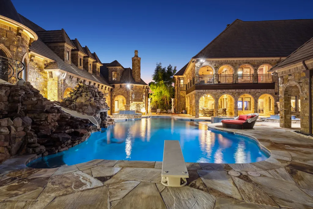 Castle Estate Heads to Auction at 6 Million as a Hilltop Masterpiece in Fort Worth 11 Nighttime view of the illuminated courtyard pool at 9553 Bella Terra Dr Fort Worth Texas featuring castle inspired stone architecture arched loggias waterfall feature and luxury resort ambiance