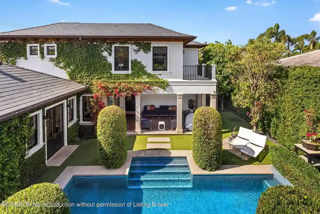 $26.9 Million North End Palm Beach Estate With Guest House and Resort-Style Grounds 16 Front exterior of 1053 N Lake Way, a luxury Palm Beach home for sale featuring Bermuda-style architecture and lush tropical landscaping.