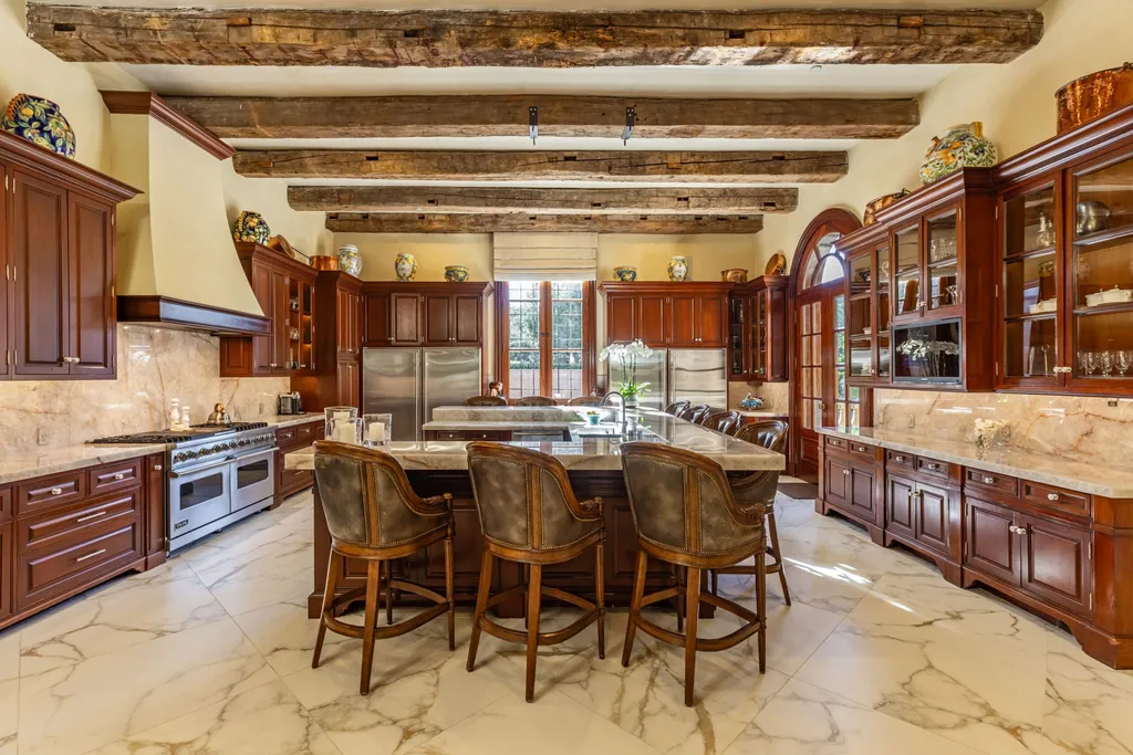 A $68,000,000 Beverly Park Estate Signals a New Era of Ultra-Scale Luxury in Los Angeles 6 Luxury kitchen inside a Beverly Park estate in Los Angeles with custom wood cabinetry, large island, marble flooring, and exposed wood ceiling beams