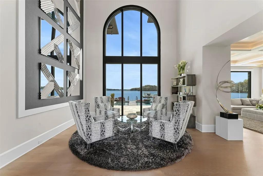 Lake Norman Estate Blends Architectural Precision With Private Waterfront Living 4 double height living room with arched window overlooking Lake Norman in a modern luxury home in Cornelius North Carolina