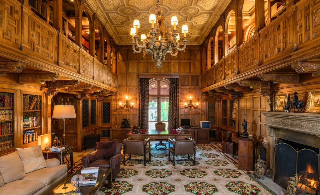The Hearst Estate in Beverly Hills: A Historic Landmark Where Hollywood Legacy Meets Market Reality 10 The Hearst Estate in Beverly Hills featuring grand two-story wood-paneled library with chandelier, fireplace, and mezzanine bookshelves