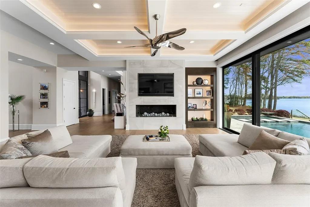 Lake Norman Estate Blends Architectural Precision With Private Waterfront Living 5 modern living room with floor to ceiling glass doors overlooking Lake Norman and pool in Cornelius North Carolina luxury home