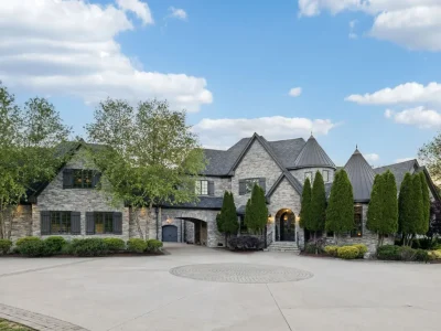 Inside a $12 Million Tennessee Estate With 62 Private Acres and Resort Amenities 1 Exterior view of a private luxury estate in College Grove Tennessee featuring stone architecture, gated driveway, and landscaped grounds