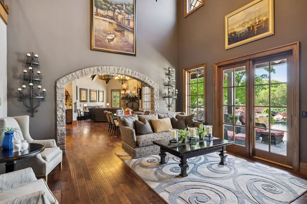 Inside a $12 Million Tennessee Estate With 62 Private Acres and Resort Amenities 3 Grand living room inside a luxury estate in College Grove Tennessee featuring high ceilings, stone archways, hardwood floors, and outdoor terrace access