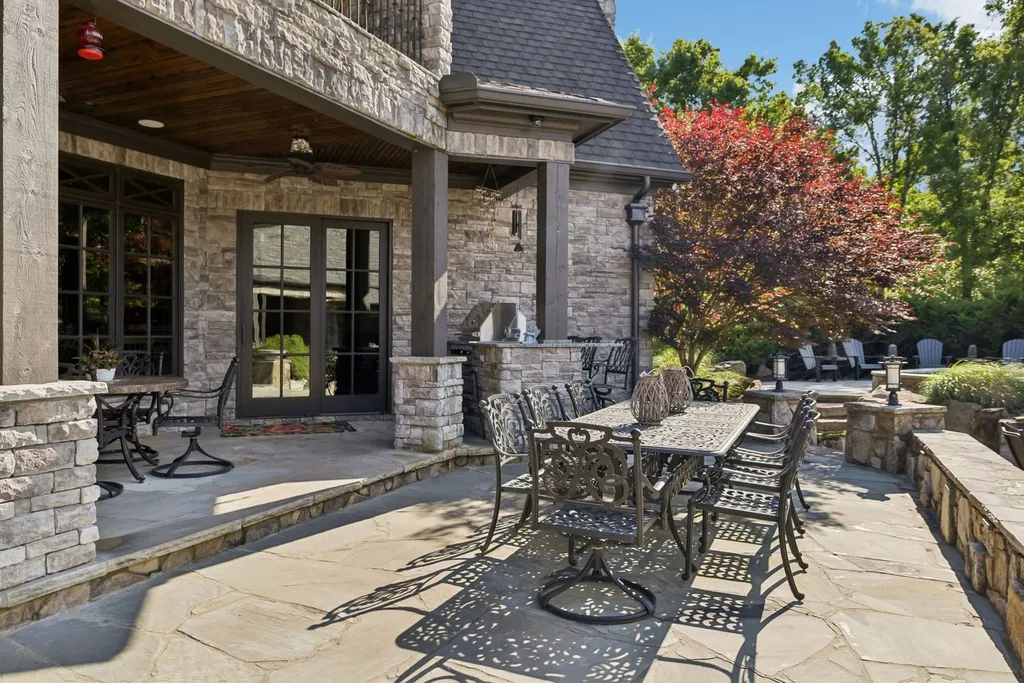 Inside a $12 Million Tennessee Estate With 62 Private Acres and Resort Amenities 13 Outdoor dining patio at a luxury estate in College Grove Tennessee featuring stone architecture, landscaped surroundings, and covered entertaining space