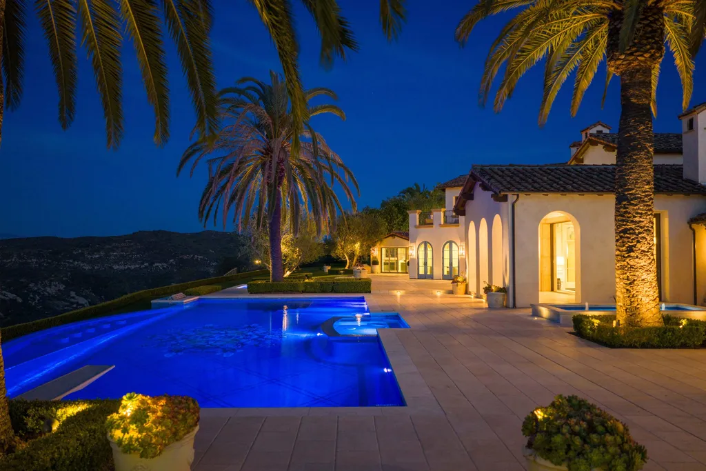 $38,500,000 Shady Canyon Estate in Irvine Blends Contemporary European Design With Nearly an Acre of Privacy 11 Resort-style infinity pool at 76 Golden Eagle in Shady Canyon illuminated at night with palm trees and panoramic hillside views