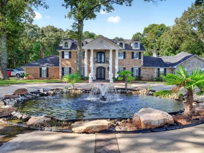 An Enchanting East Texas Estate With Three Furnished Woodland Cabins Asks $2,500,000 2 16104 County Road 294, Arp: a columned brick residence stands beyond a landscaped fountain and circular drive.