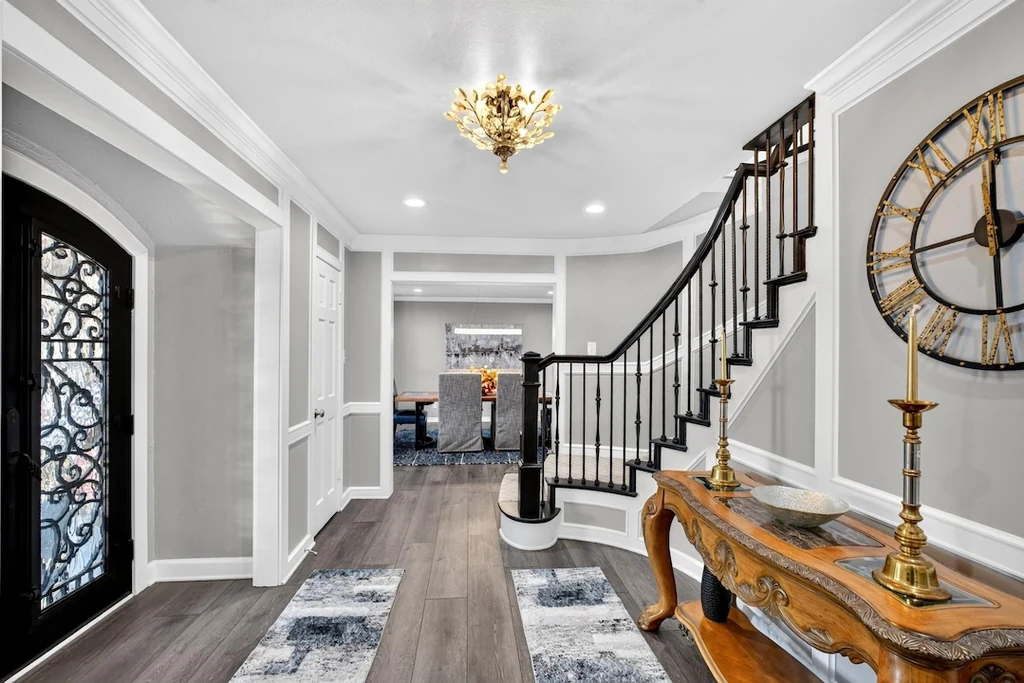 16104 County Road 294 – Curved Staircase Foyer 16104 County Road 294, Arp: a curved staircase and decorative iron entry door define the pale gray foyer.