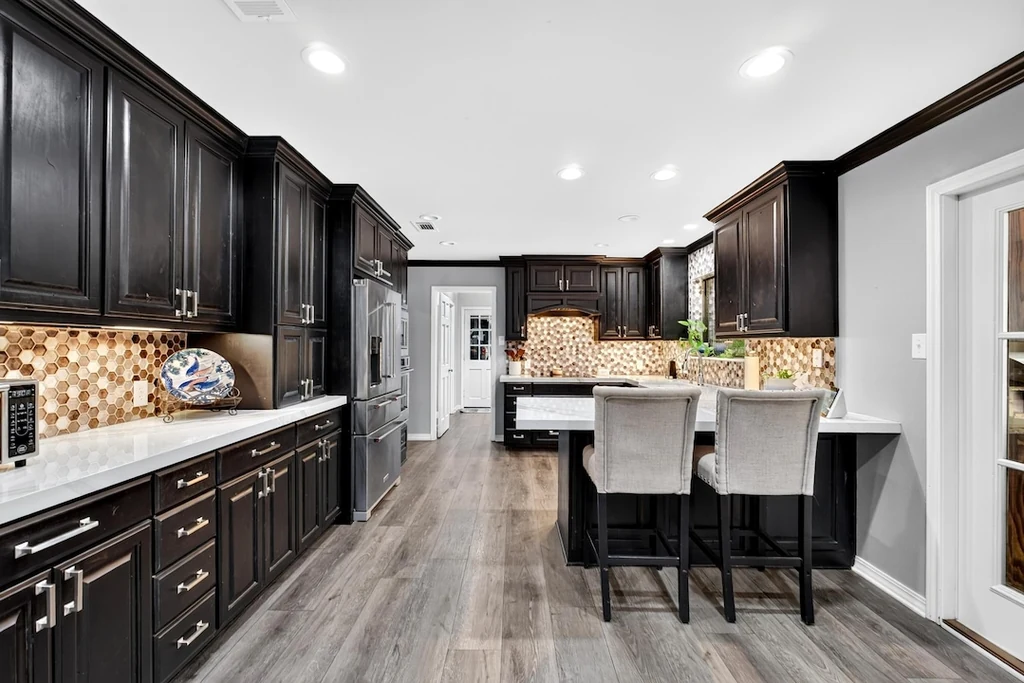 16104 County Road 294 – Island Kitchen 16104 County Road 294, Arp: dark cabinetry and pale counters surround the kitchen island and breakfast seating.