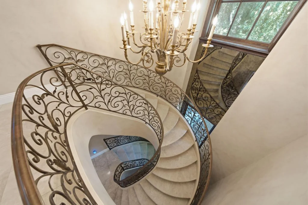 10285 Magdalena Rd – Curved Staircase 10285 Magdalena Rd, Los Altos Hills: a curved staircase winds around an elaborate iron balustrade.