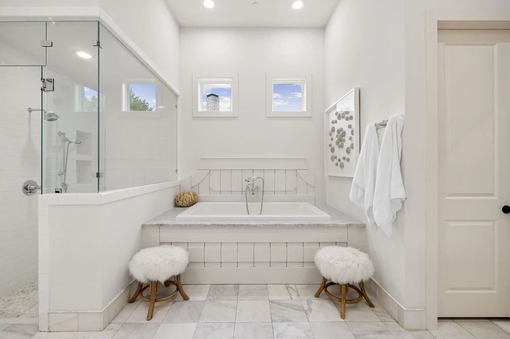1255 Bolton Ct – Primary Bathtub 1255 Bolton Ct, Southlake: a long upholstered bench sits beneath the raised bathtub and high windows.
