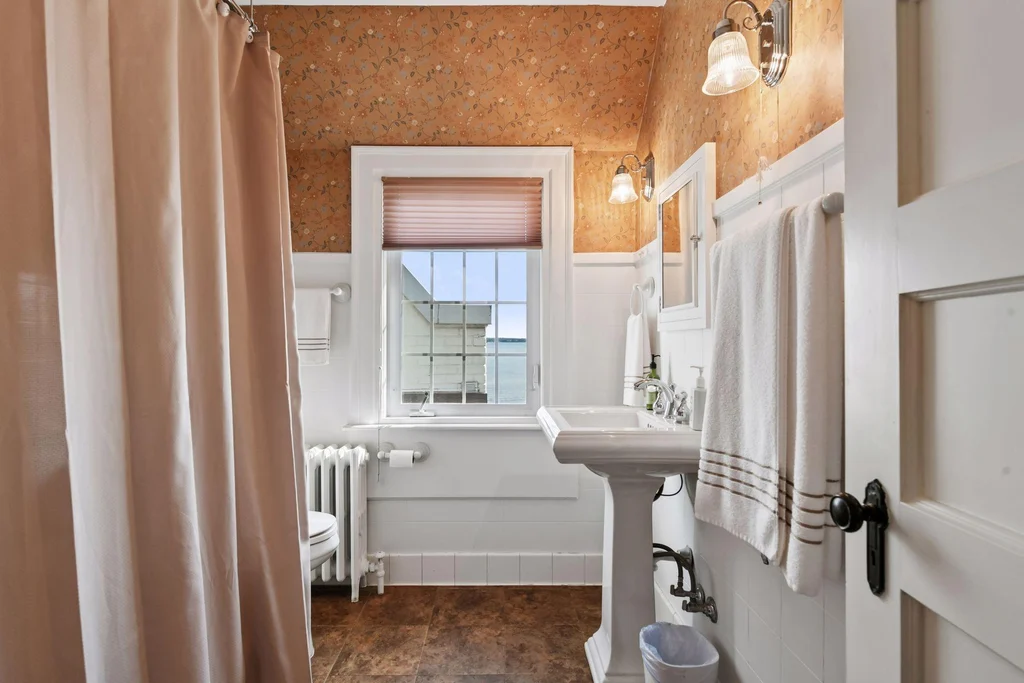 1305 Shoreline Dr — Bathroom Interior A bathroom pairs a pedestal sink with tall windows and warm wall finishes at 1305 Shoreline Dr.