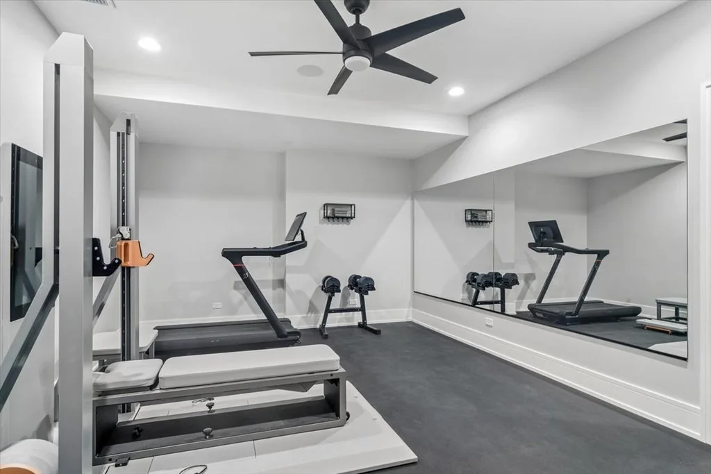 Inverness Estate With a Speakeasy-Style Lounge and Indoor Golf Simulator Lists for $2,750,000 16 Home gym with mirrored walls, exercise equipment and dark flooring in Inverness, Illinois