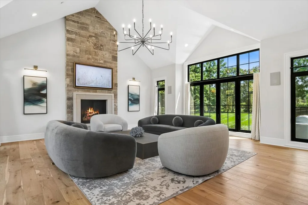 Inverness Estate With a Speakeasy-Style Lounge and Indoor Golf Simulator Lists for $2,750,000 3 Vaulted great room with a stone fireplace and black-framed windows in Inverness, Illinois