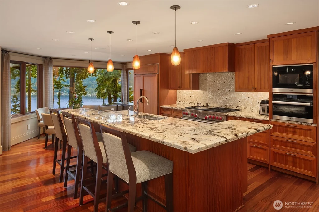 Pocket Doors Open to a Lake-View Pavilion at This Sammamish Estate Asking $6,880,000 7 Wood-cabinet kitchen with a tiered granite island and upholstered counter seating