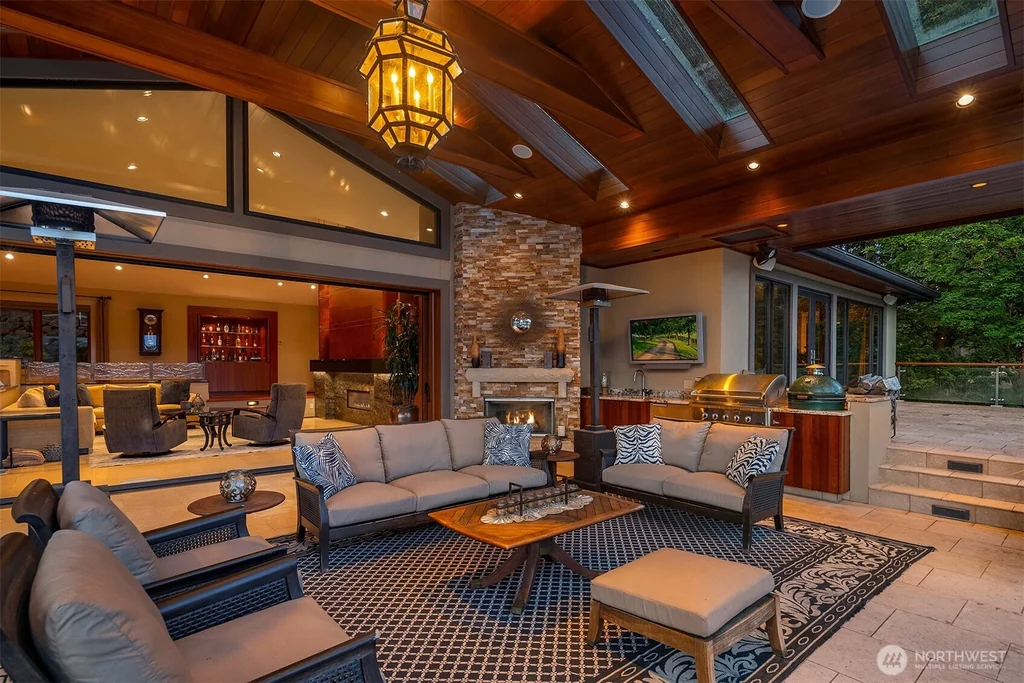 Pocket Doors Open to a Lake-View Pavilion at This Sammamish Estate Asking $6,880,000 10 Covered outdoor lounge with a stone fireplace beside the open interior