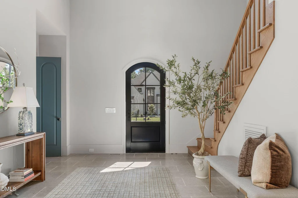 Limestone Foyer Staircase | 6744 Brixley Crest Ct A limestone foyer introduces the staircase and an arched front door at 6744 Brixley Crest Ct, Raleigh.