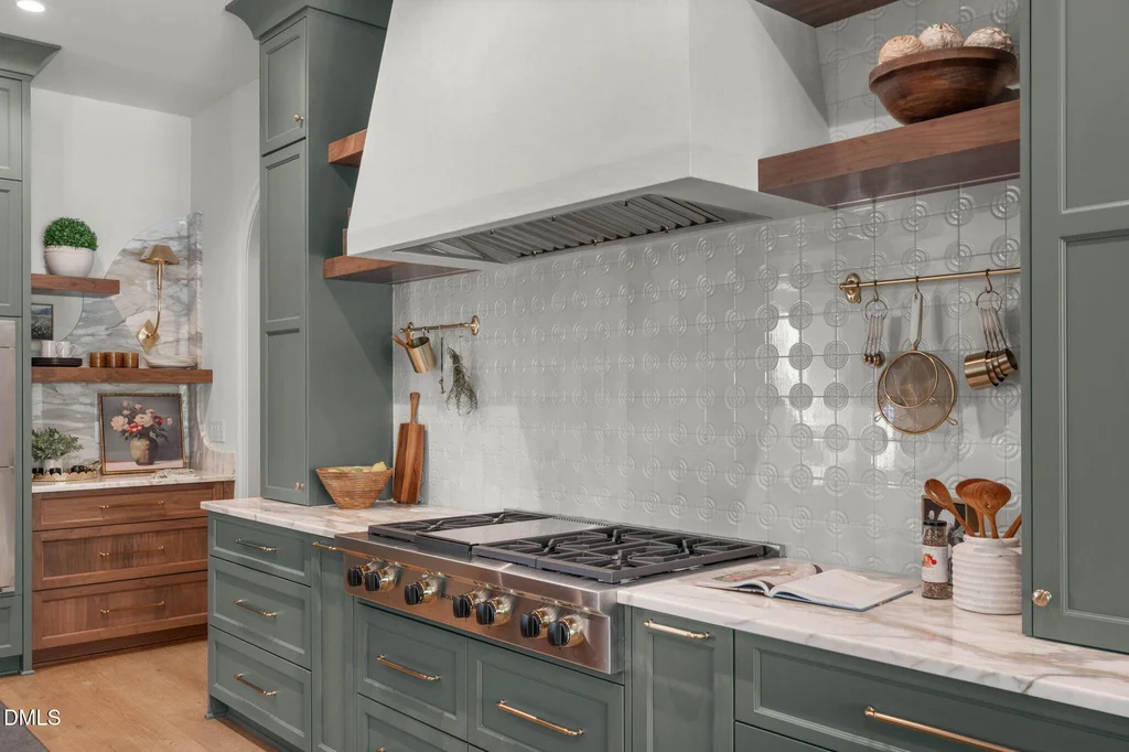 Wolf Range Top Kitchen | 6744 Brixley Crest Ct The kitchen’s Wolf range top sits beneath a substantial custom hood at 6744 Brixley Crest Ct, Raleigh.